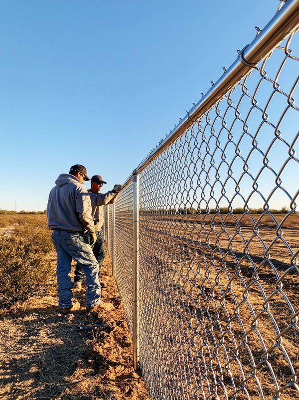A repaired chain link line standing straight and tight along a back property line